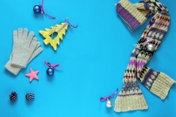 Christmas decorations, woolen scarf and gloves on a blue bright background, top view, congratulations, postcard