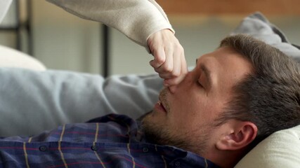 A woman in bed struggles with her husband's snoring. The woman covered her husband's nose