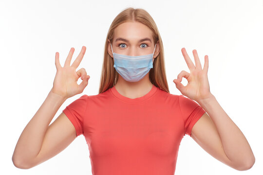 European girl in a medical mask, shows ok. Conceptual photo on the theme of the Covid 2019 pandemic.