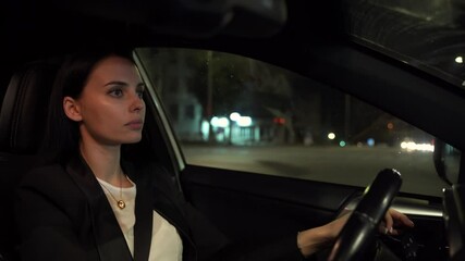 Focused elegant woman driving car at night Young brunette in jacket driving car confidently on city street late at night looking forward