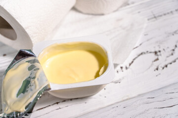 Pack of yogurt with tiolet paper on white wooden desk.