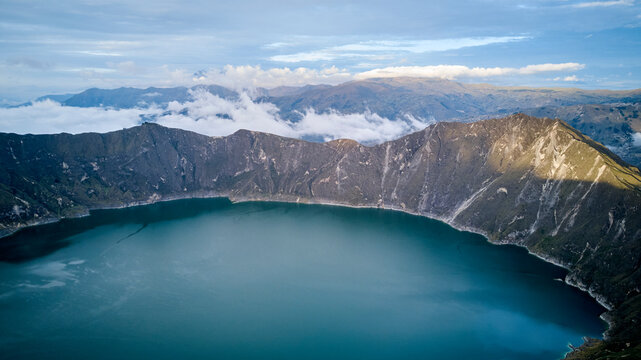 Aerial of beautiful quilotoa crater lake in Ecuador, South America with turquoise water inside a volcanic caldera with snow capped andes mountains in the background, famous for hikers and back packers © Jens