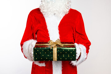 Santa Claus with beard and in red costume holds green wrapped gift. New Year concept on white background