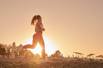 Beautiful sportive woman silhouette in sportswear jogging in the morning dawn