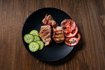 pork with vegetables on a black plate