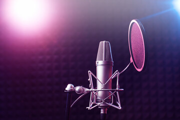 Fototapeta na wymiar Professional microphone close up in recording studio in neon pink blue lighting, karaoke concept