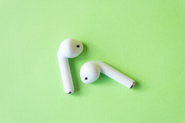 Wireless white headphones on a green background. 