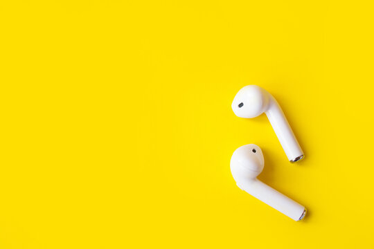 Wireless white headphones on a yellow background., place for text. 