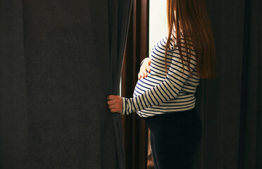 The pregnant woman standing at the window
