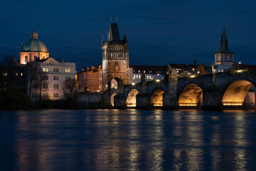 Fototapeta na wymiar .Charles Bridge in the early evening and illuminated street lights in the center of Prague and reflections on the river Vltava light