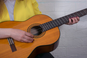 Beautiful young woman with brown guitar in studio close up