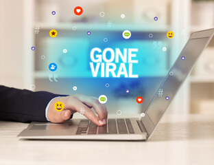 Freelance woman using laptop with GONE VIRAL inscription, Social media concept