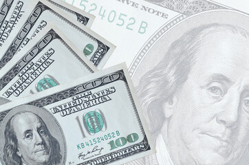 100 US dollars bills lies in stack on background of big semi-transparent banknote. Abstract...