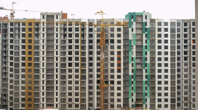 A tower crane is being dismantled into sections against the backdrop of a new building. Jib crane vertical disassembling 4k