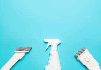 Vacuum cleaner attachments and spray cleaner on a blue background, top view, copy space. Cleaning supplies.