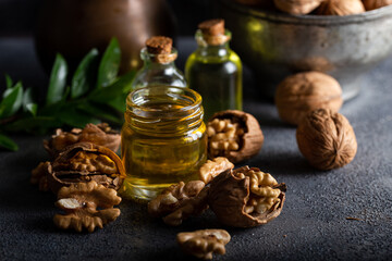 Cosmetic and therapeutic walnut oil on wooden background. Walnut oil in bottle and nuts on a dark background.