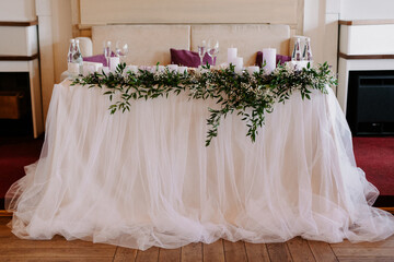 the presidium of the newlyweds in the banquet hall of the restaurant is decorated with candles and green plants
