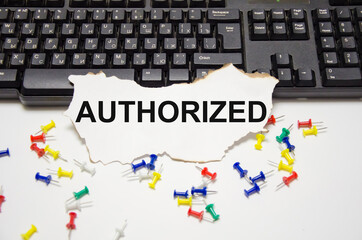 Obraz premium the word authorized is written on a white sheet of paper that lies on a computer keyboard and on a white background, next to it are multi-colored paper clips