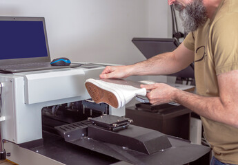 textile printing worker preparing machine for customization in sneakers