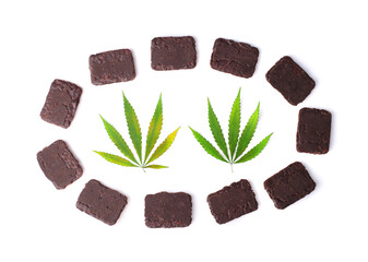 Two green hemp or cannabis leaves on white isolated background in a circle of chocolate cookies in a rectangular shape