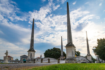 Prato della Valle, Padua, panorama of the obelisks and statues that lead to one of the bridges in the square, in a splendid sunny day with blue sky and clouds Padua Veneto, Italy.