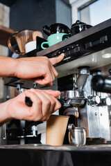 Fototapeta na wymiar cropped of barista pushing button on coffeemaker while preparing coffee to go