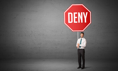 Obraz premium Young business person holding road sign with DENY inscription, new rules concept