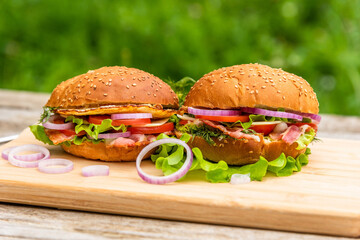 Two delicious hamburgers with bacon, lettuce, and chopped onions.