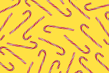 Christmas or New Years festive background with a repeating pattern of Santa's lollipop cane sticks. White cane with red stripes on a yellow illuminated trend background.