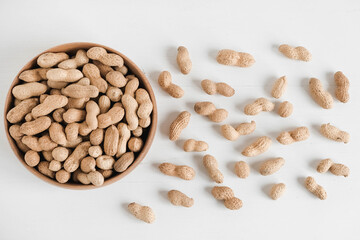 Dry peanuts in a wooden bowl on a white background. Top view. Copy, empty space for text