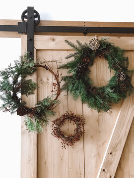 Christmas rustic wreaths with pinecones and berries on wooden rustic doors in room