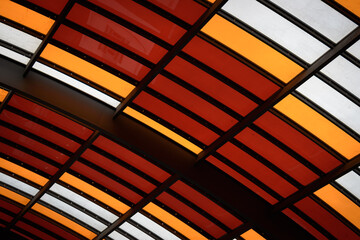 Architectural detail of the structure of a modern cover with metal frame and coloured glass curved panels in Amsterdam bus station