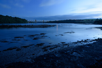 Dusk landscape of the Menai Strait with the Britannia Bridge in the background. Blue scenery with clouds and sea.