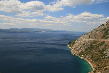 Obraz premium The mountainous coast of the island of Hvar in Croatia. In the background is a blue sky with white clouds.