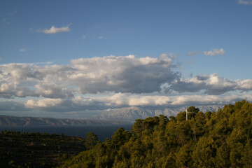 The mountainous coast of the island of Hvar in Croatia. In the background is a blue sky with white clouds.