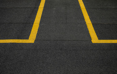 Abstract texture composition in the form of yellow boundary warning lines painted with paint on a dark gray background. The natural texture of the bituminous coating on the roof of the house.