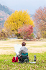 秋の湖畔の黄葉した風景を描く人、河口湖