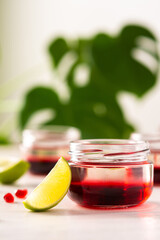 Red alcoholic shots on white background , small jars with liquor and grenadine with lime
