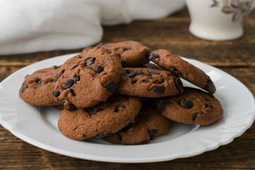 Homemade chocolate chip cookies with chocolate drops on a white plate. Homemade chocolate biscuits close up. Soft focus