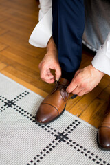 A man tying up brown shoes close  up 