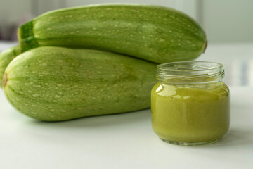Children's squash puree in a glass jar on a background of squash. Children's food. Food for the first feeding of the baby. Healthy eating.