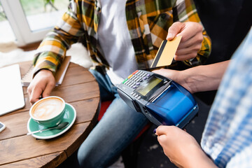 Cropped of barista holding payment terminal near client with credit card