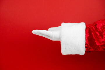  Santa Claus hand presents your Christmas text or product on red background with copy space