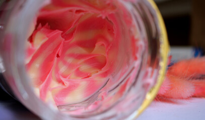 Opened glass jar with mixed pink and white sweet tasty cream. Breakfast.