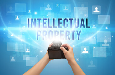 Close-up of hand holding camera with INTELLECTUAL PROPERTY inscription, video surveillance concept