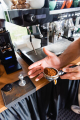 partial of barista holding portafilter while preparing coffee in bar