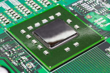 Macro-sized perspective photo of a computer processor, soldered onto a green motherboard,...