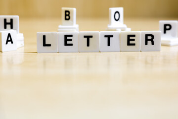 A row of small white plastic tiles, containing the letters forming the word letter, to represents the concept of alphabetic letters.