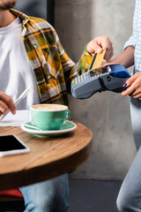 cropped of waiter holding payment terminal near man with credit card