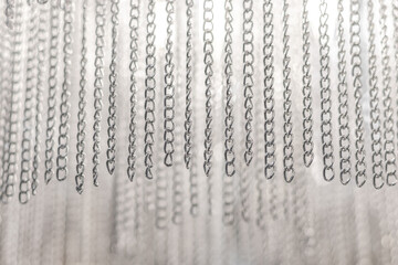 Silver chains on a light background hanging from above. Copy space. Wallpaper for the design.